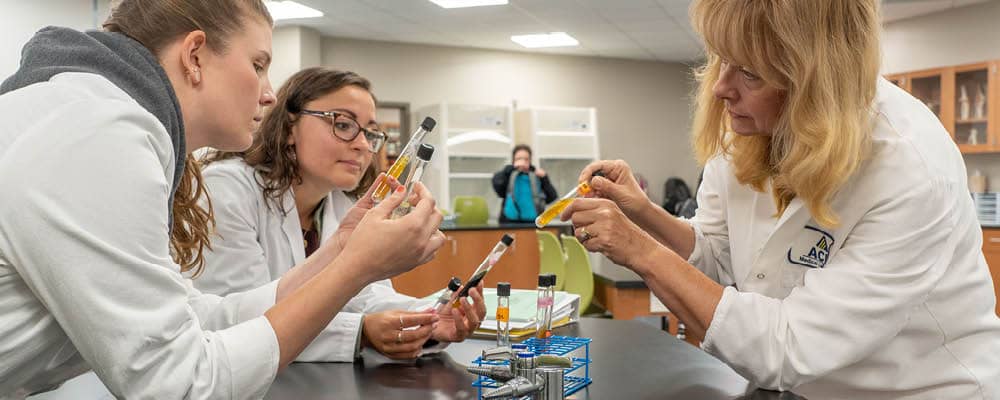 Two FLCC students and a professor studying chemicals.