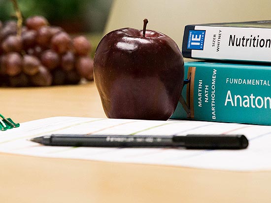 Nutrition and anatomy textbooks with fruit next to them