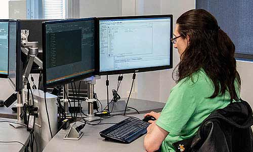 Student working on computer with dual screen monitor