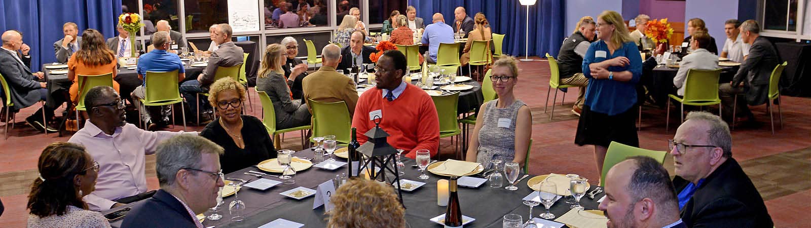 FLCC employees gathered around tables in a room, enjoying a meal together.