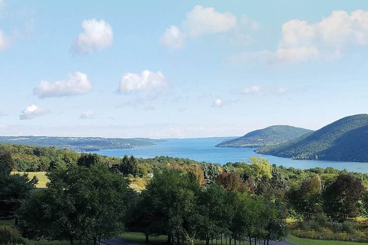 A stunning summer landscape showcasing Canandaigua Lake and its surrounding hills.