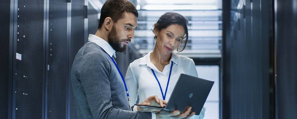 Two computing science professions look at a laptop screen together.