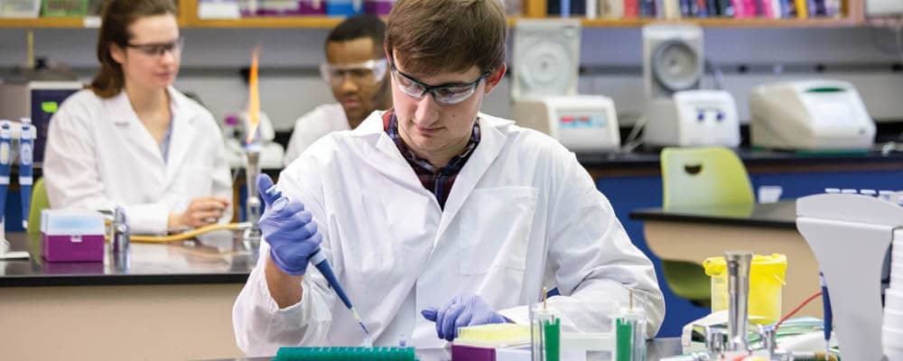 Student in biotechnology lab using a pipette