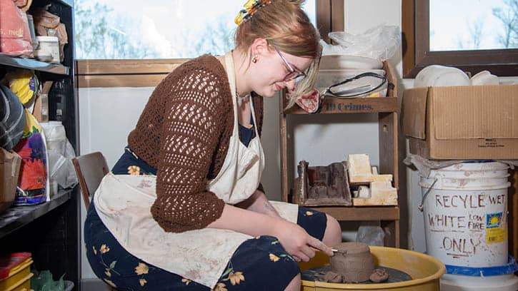 Student creating a clay sculpture in the ceramics studio.