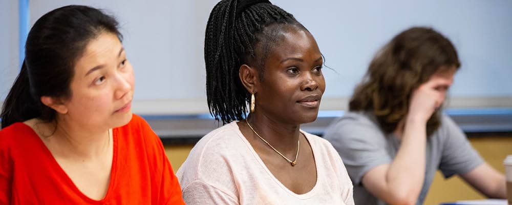 Three students focus their attention toward an instructor at the front of an FLCC classroom.