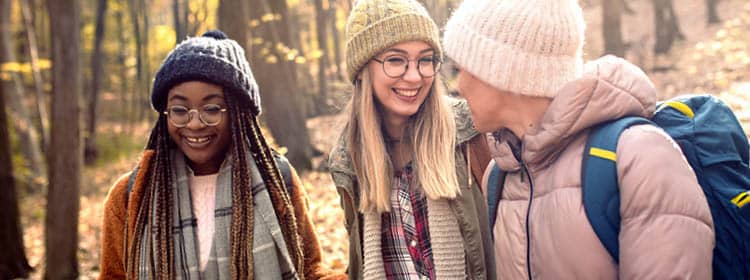  Three students walking on a wooded nature trail.