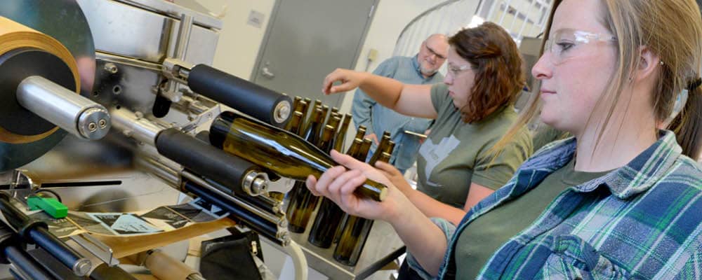 Students using labeling equipment at the Viticulture and Wine Center